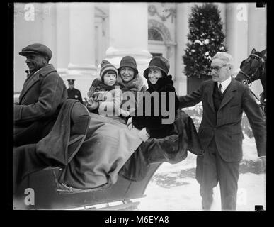 First Lady Grace Coolidge (center), seated by Chief White House Usher Ike Hoover (right), enjoys a sleigh ride on White House grounds with unidentified woman, child and driver, Washington, DC, 1929. Stock Photo