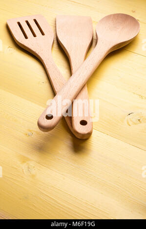 Wooden Kitchen Utensils on yellow work surface Stock Photo