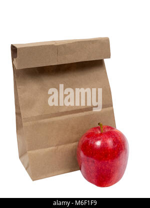 Vertical shot of a brown paper bag with the top folded down and a a red shiny apply sitting in front of it on a white background. Stock Photo