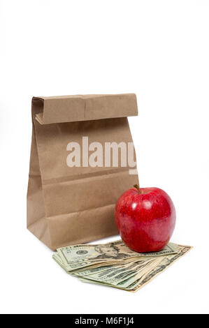 Vertical shot of the front of a brown paper bag with the top folded down with a red shiny apple sitting on fanned out twenty dollar bills and a ten do Stock Photo