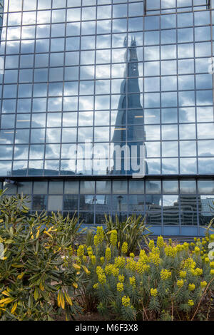 A different and unusual atmospheric angle or viewpoint of the shard office building in central london reflected in a large glass commercialor business Stock Photo