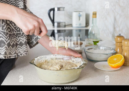 Mixing the dough. Female hands knead dough in modern minimalistic kitchen, close-up view Stock Photo