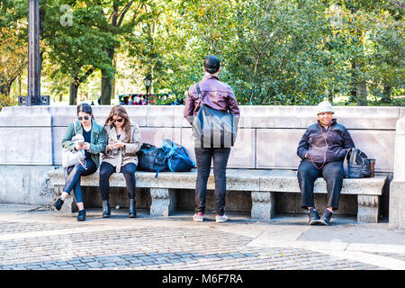 New York City, USA - October 28, 2017: Midtown Manhattan with people sitting on benches by Columbus Circle, Central Park entrance on sunny day closeup Stock Photo