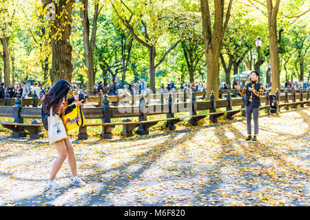 New York City, USA - October 28, 2017: Manhattan NYC Central park with people standing on road in autumn fall season with fallen leaves on ground, asi Stock Photo