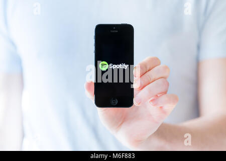 Herndon, Virginia - February 28, 2018: Black iPhone 5 apple phone smartphone mobile screen for spotify music app application, isolated, fingers, hand, Stock Photo