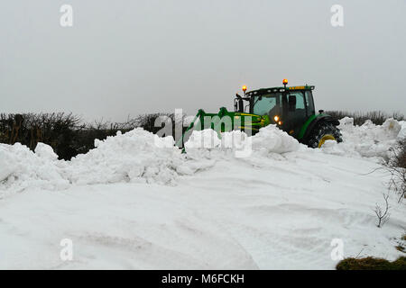 Compton Valence, Dorset, UK.  3rd March 2018.  UK Weather.  A contractor with a tractor and digger attachment clearing the last of the roads blocked by snow drifts from Strom Emma on Eggardon Hill near West Compton in Dorset.  The snow is begining to thaw with most of the fields almost snow free but the drifts along the roads remain and in places are 4-5 feet high.  Picture Credit: Graham Hunt Photography Credit: Graham Hunt/Alamy Live News Stock Photo
