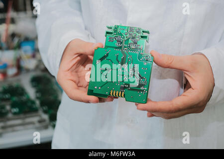 Technician with computer circuit board with chips. Spare parts and components for computer equipment. Production of electronics and maintenance. The concept of high technology. Stock Photo