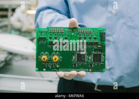 Technician with computer circuit board with chips. Spare parts and components for computer equipment. Production of electronics and maintenance. Stock Photo