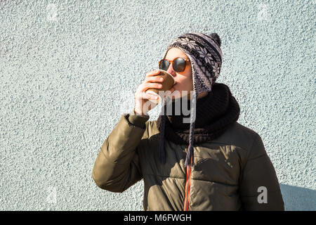 Young man drinks coffee from paper cup outdoors. Stock Photo
