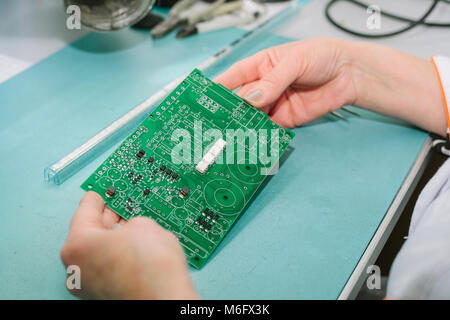 Female computer expert professional technician examining board computer in a laboratory in a factory. Stock Photo