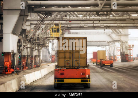 Automated vehicles moving shipping containers to and from gantry cranes in a port container terminal. Stock Photo