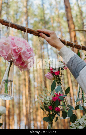 The decorator is working. Wedding flowers decoration arch in the forest. The idea of a wedding flower decoration. Stock Photo