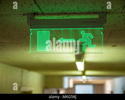 Indoor view green emergency fire exit sign on ceiling.