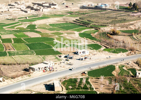 Aerial photo of a road between small villages between Ghazni and Kabul in Afghanistan with green fields and a gas station Stock Photo