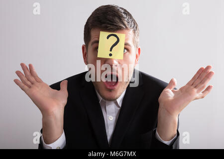 Close-up Of A Young Businessman With Sticky Notes On His Forehead Showing Question Mark Sign Stock Photo