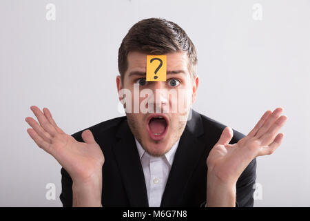 Close-up Of A Young Businessman With Sticky Notes On His Forehead Showing Question Mark Sign Stock Photo