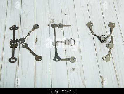 The word key is laid out on a white surface of old steel keys. Stock Photo