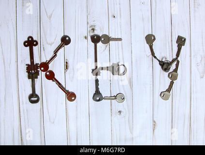 Old metallic different keys are laid out on a light background in the shape of a word key. Stock Photo