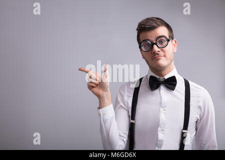 Young Man Wearing Spectacles Pointing On Grey Background Stock Photo
