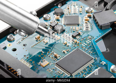 Soldering iron fixing blue microcircuit - close up studio shot Stock Photo