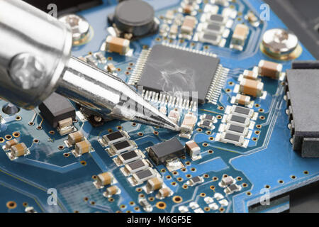 Soldering iron and blue microcircuit - close up studio shot Stock Photo