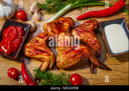 Fried chicken wings and vegetables on a wooden background Stock Photo