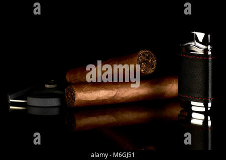 Cigar with cutter and lighter, reflected on a glass table on a black background Stock Photo