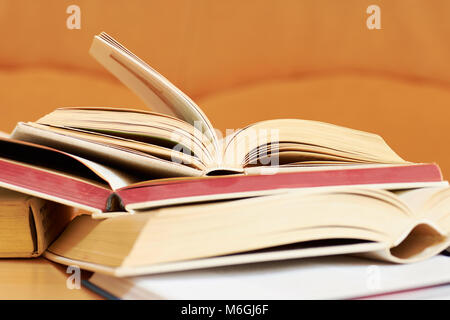 Open books in a hard cover on a table with a blurred orange background Stock Photo