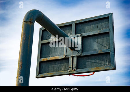 Back view of green basketball shield on a metal pole against a cloudy sky Stock Photo