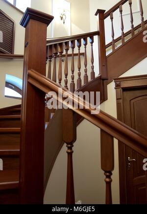 Spiral wooden staircase with balusters pillars and a massive handrail in a classical style Stock Photo