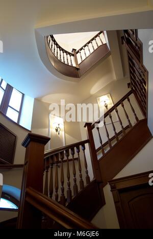 Spiral wooden staircase with balusters pillars and a massive handrail in a classical style Stock Photo