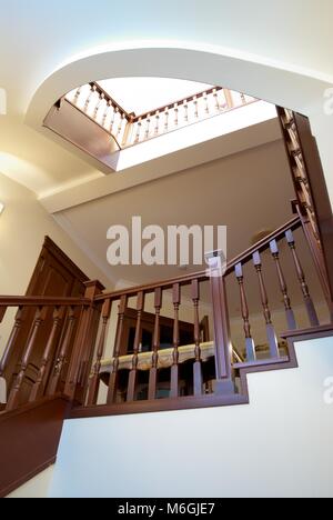 Spiral wooden staircase with balusters pillars and a massive handrail in a classical style Stock Photo