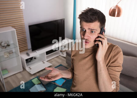 Worried Young Man Talking On Phone About House Robbery Stock Photo