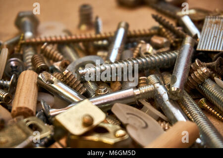 Close up view of variety of screws, nails, bolts, and other hardware products of various metals are strewn across a workstation Stock Photo