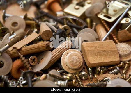 Close up view of variety of screws, nails, bolts, and other hardware products of various metals are strewn across a workstation Stock Photo