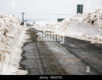East Lothian, Scotland, United Kingdom, 4th March 2018. UK Weather:   Two cars buried in snow on the Drem to Haddington road after heavy snowfall as a result of the extreme weather event, nicknamed the 'Beast from the East. High banks of snow create a narrow passage Stock Photo