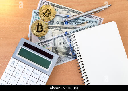 Two golden bitcoins, journal, pen, and calculator on us dollars top view Stock Photo