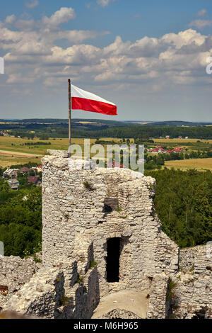 Polish national flag fluttering on the defensive tower of the castle in Ogrodzieniec, in the background a beautiful summer landscape of the area Stock Photo