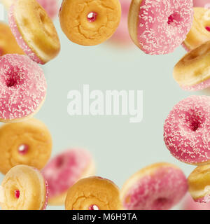 Falling or flying pink glazed doughnuts with sprinkles in motion at pastel blue background , frame Stock Photo