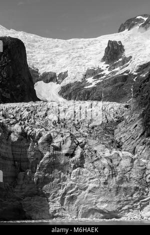 The imbedded rocks are clearly visible in layers of this glacier flowing down a narrow valley Stock Photo