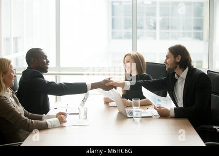 Multiracial businessmen in suits handshaking at executive team o Stock Photo