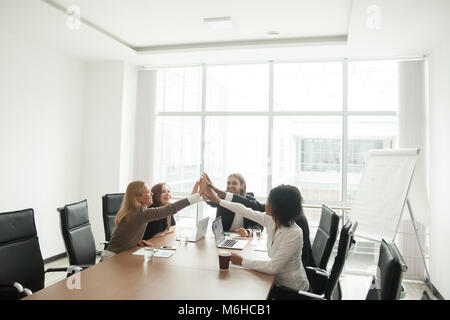 Happy businesspeople giving high-five at office meeting, celebra Stock Photo