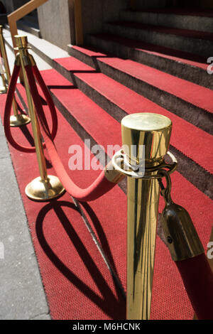 Brass Stanchions and velvet ropes guard red carpet steps, New York City, USA Stock Photo