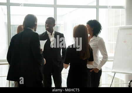 Diverse smiling business people having conversation standing tog Stock Photo