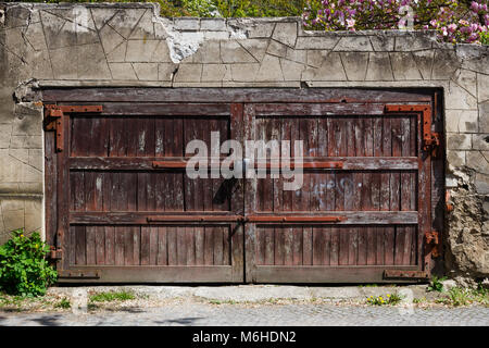 Old brown wooden gate with lock in a stone fence Stock Photo