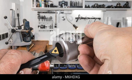 Detail of tool bit and metallic bolt in workman's hands. Handy man's workshop with a drill, a vice and various tools. Idea of engineering and industry. Stock Photo