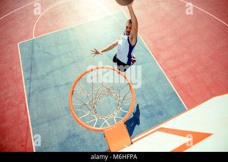 High angle view of basketball player dunking basketball in hoop Stock Photo