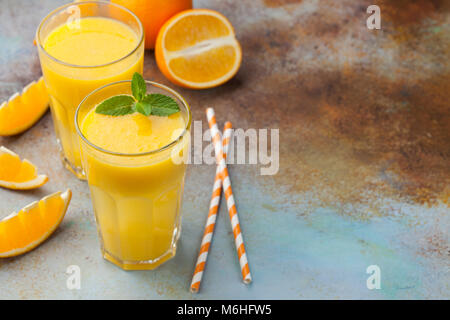Two glasses with freshly squeezed orange juice and mint on an old rusty blue background. Top view with copy space. Stock Photo