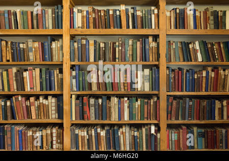 Very old hardcover books with worn bindings on pine shelves in the Whalers Church in Grytviken South Georgia. Stock Photo