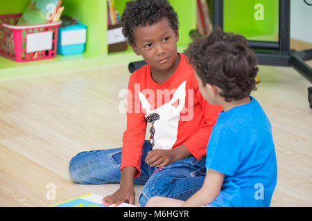 Two boy kid  sitting on floor and taking in preschool library,Kindergarten school education concept.diversity children Stock Photo